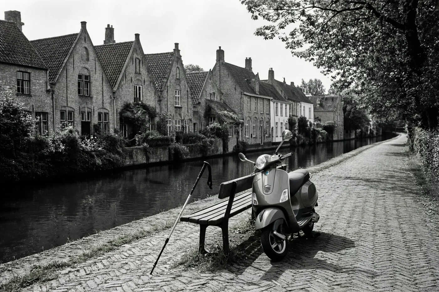 Een zwart-witfoto toont een step en een wandelstok op een bank bij een kanaal met traditionele gevelhuizen langs het water.