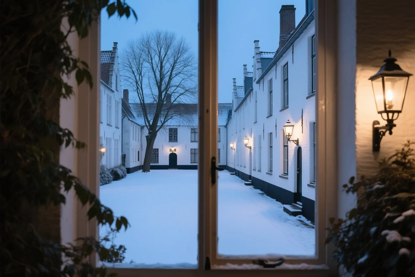 Door een open deuropening is een besneeuwd Brugs begijnhof te zien met witte huizen, kale bomen en warme lantaarns in de blauwe schemering.