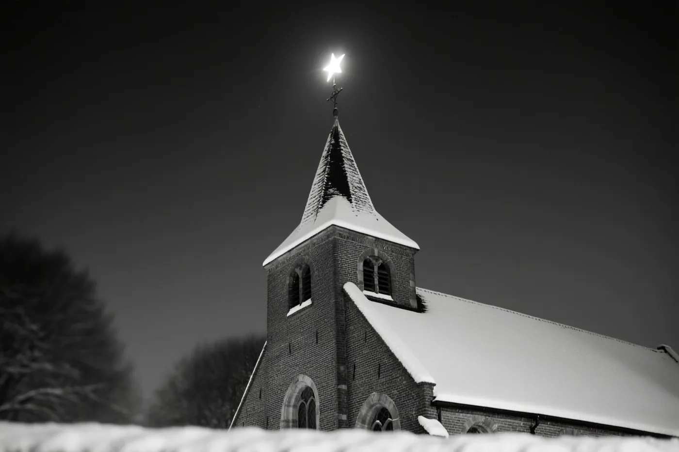 Een zwart-witbeeld toont een besneeuwde Vlaamse kerk bij nacht met een heldere ster boven het dak en de toren.