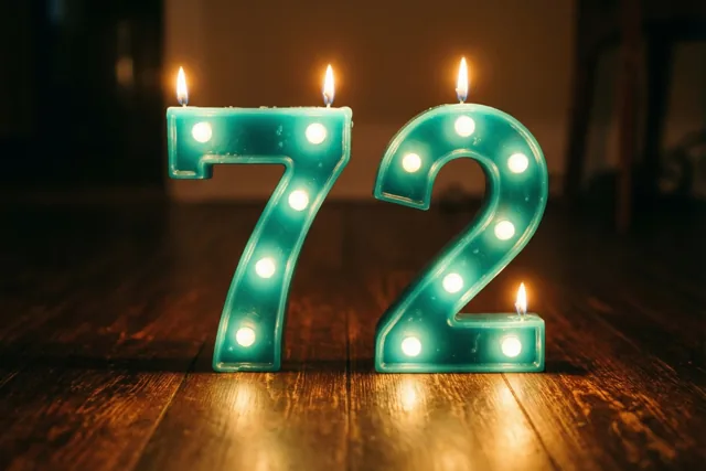 Twee blauwgroene kaarsen in de vorm van 7 en 2 staan met ingebouwde lichtjes en kleine vlammetjes op een donkere houten vloer.