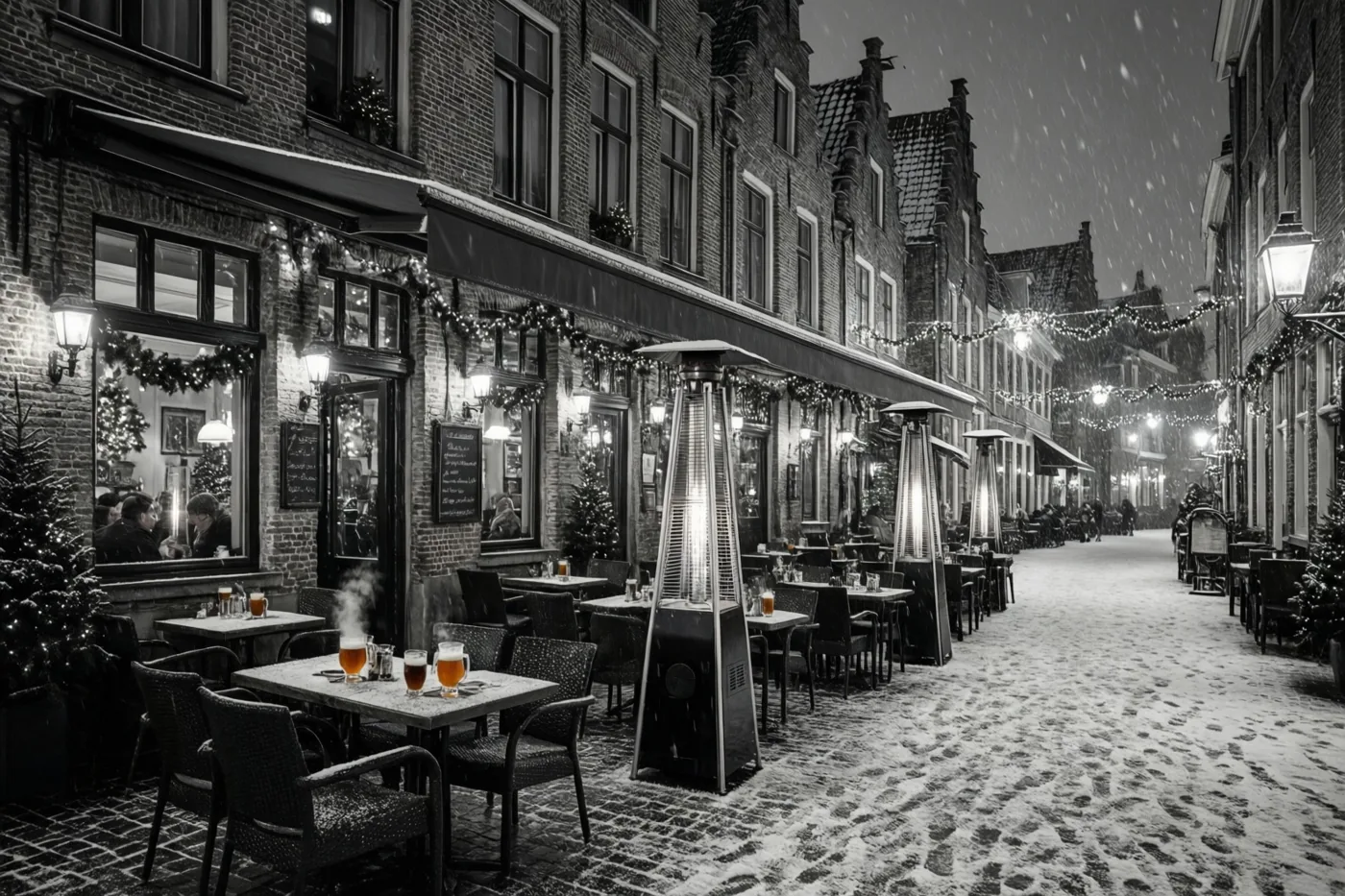 Langs een besneeuwde kasseistraat met bakstenen gebouwen staan cafétafels met dampende glühwein en terrasverwarmers onder kerstlichtjes en slingers terwijl er sneeuw valt.