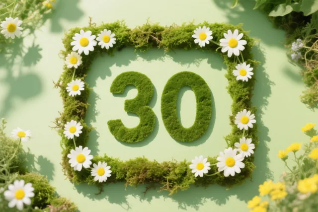 Het getal 30 is gevormd uit groen mos en omlijst met een mosrand en witte madeliefjes tegen een lichtgroene achtergrond.