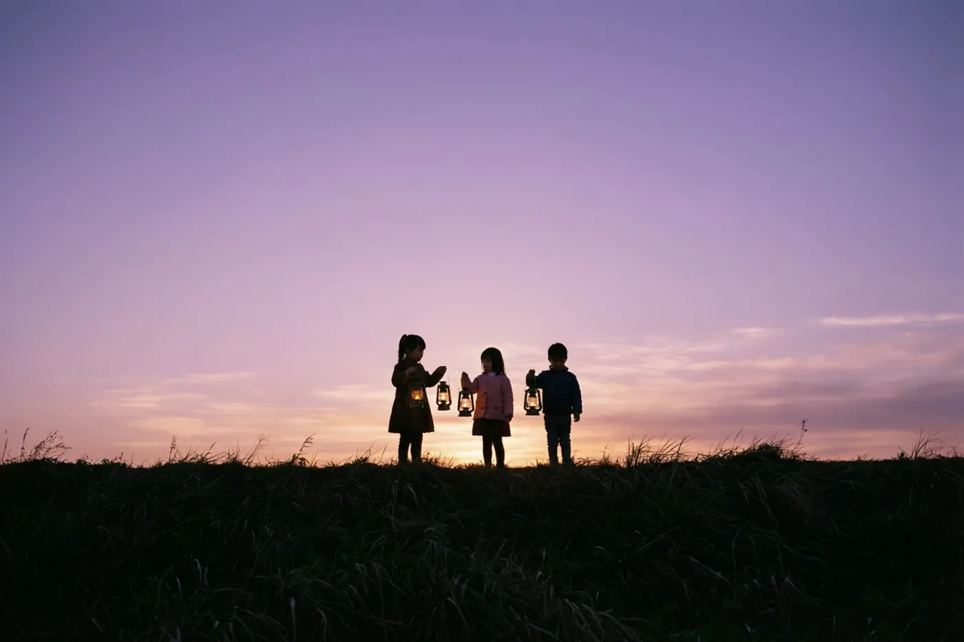Drie kleine kinderen staan als silhouetten op een met gras begroeide dijk, elk met een brandende lantaarn tegen een roze en paarse schemerhemel.