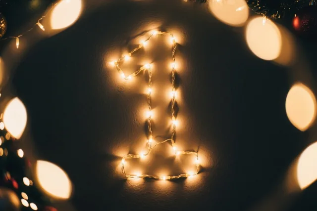 Warme lichtjes vormen het cijfer 1 op een donkere muur, met wazige lichtjes op de achtergrond.