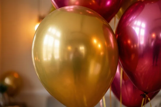 Gouden en roze folieballonnen weerspiegelen elkaar in zacht warm feestlicht, met een onscherpe achtergrond.