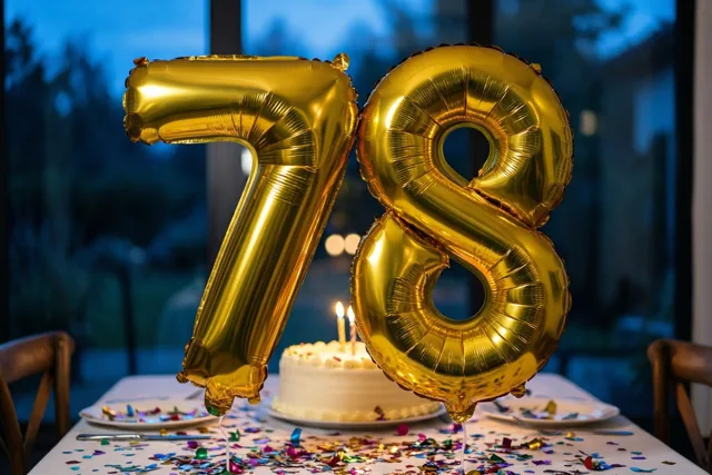 Gouden folieballonnen vormen 78 boven een tafel met kleurrijke confetti en een kleine taart met brandende kaarsen, voor een onscherp blauw raam bij schemering.