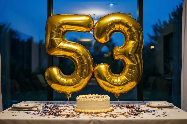 Twee grote gouden folieballonnen in de vorm van 5 en 3 zweven boven een tafel met een witte taart en confetti, met een blauwe avondlucht achter het raam.