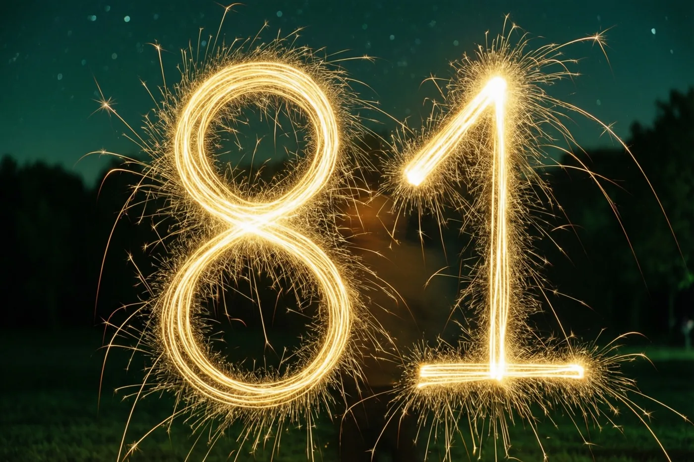 Gouden lichtsporen van sterretjes vormen het getal 81 buiten in het donker, tegen een groenige achtergrond met vage lichtjes.