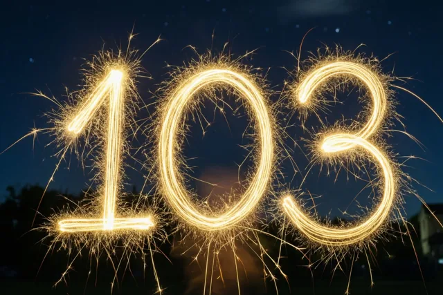 Gouden lichtsporen van sterretjes vormen 103 tegen een donkere nachthemel met zwak zichtbare sterren.