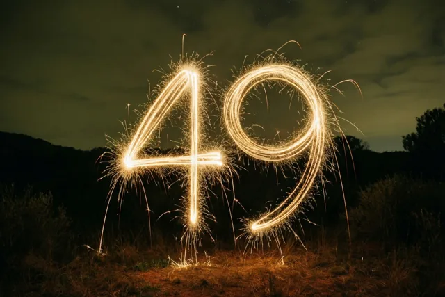 Gouden lichtsporen van sterretjes vormen 49 tegen een donkere nachthemel met heuvels op de achtergrond.