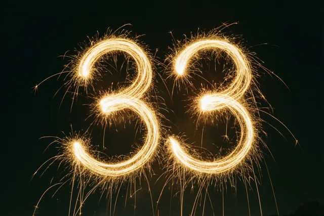 Goudkleurige lichtsporen van sterretjes vormen het getal 33 tegen een donkere nachthemel.