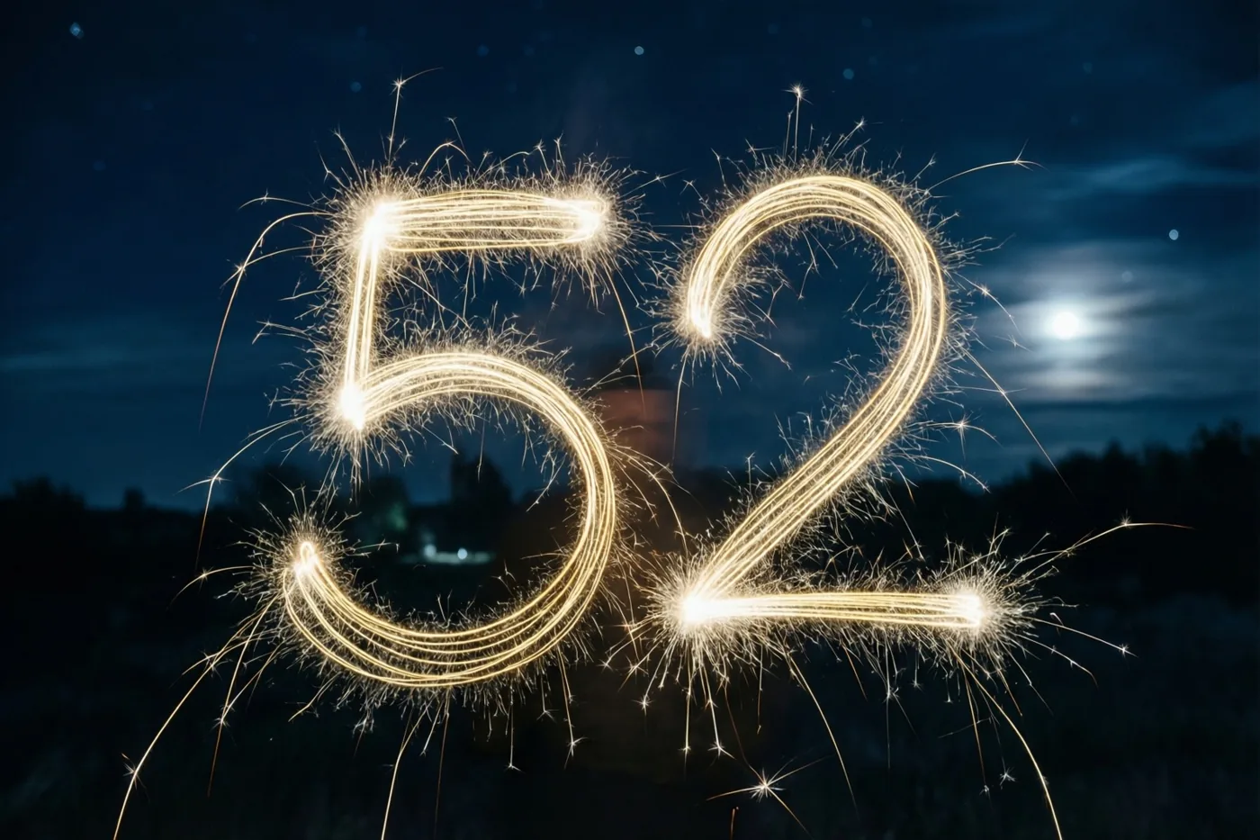 Gouden lichtsporen van sterretjes vormen het getal 52 tegen een donkere nachthemel met een zichtbare maan.