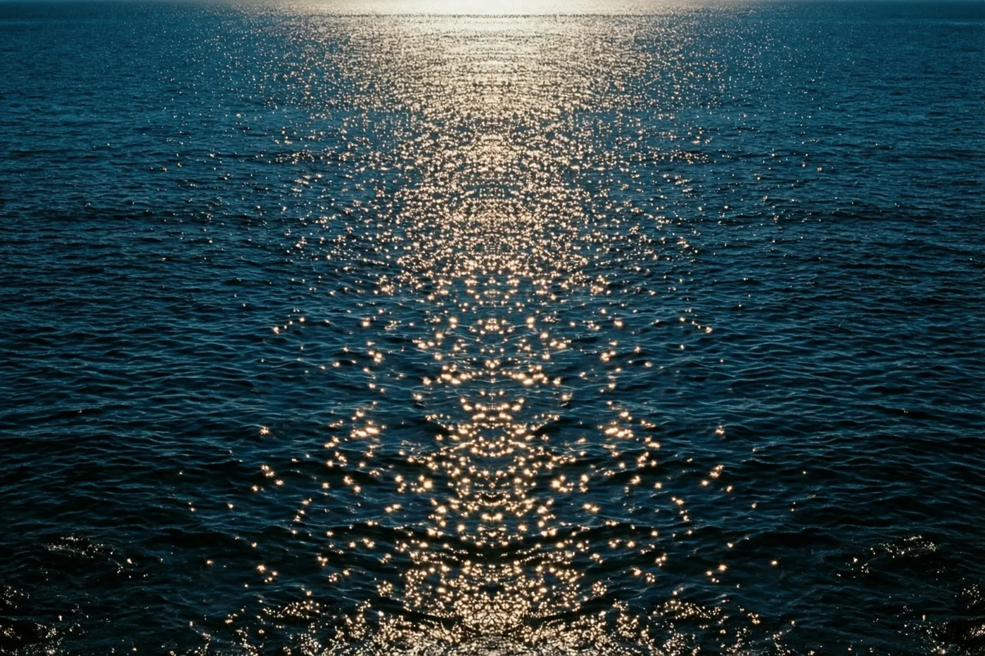 Kleine goudgele lichtpuntjes schitteren op het diepblauwe zeewater.
