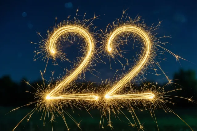 Gouden lichtsporen van sterretjes vormen 22 tegen een donkerblauwe en zwarte nachthemel.