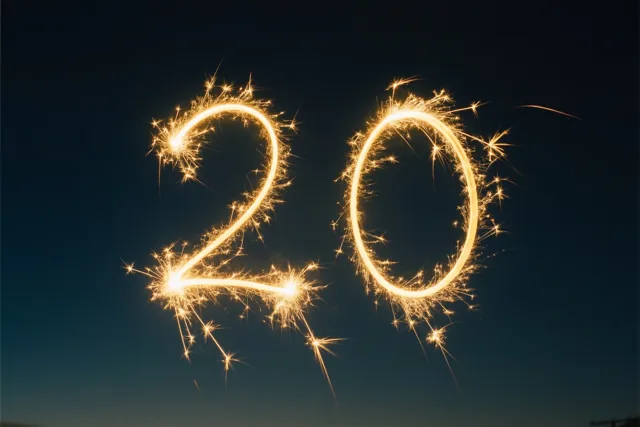 Gouden lichtsporen van sterretjes vormen het getal 20 tegen een donkere nachtlucht.