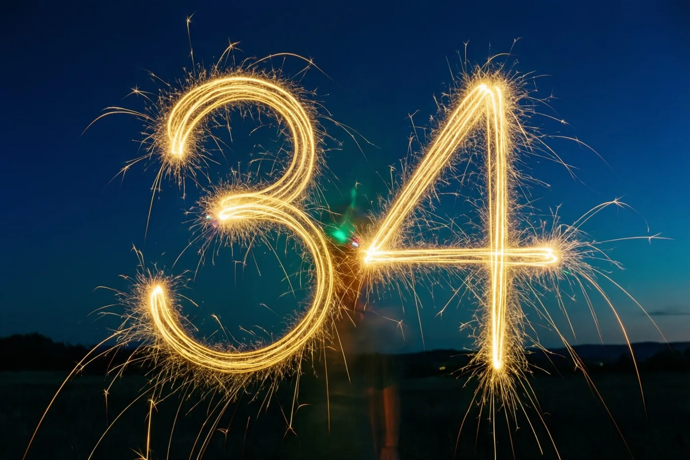 Gouden lichtsporen van sterretjes vormen het getal 34 tegen een donkerblauwe nachthemel.