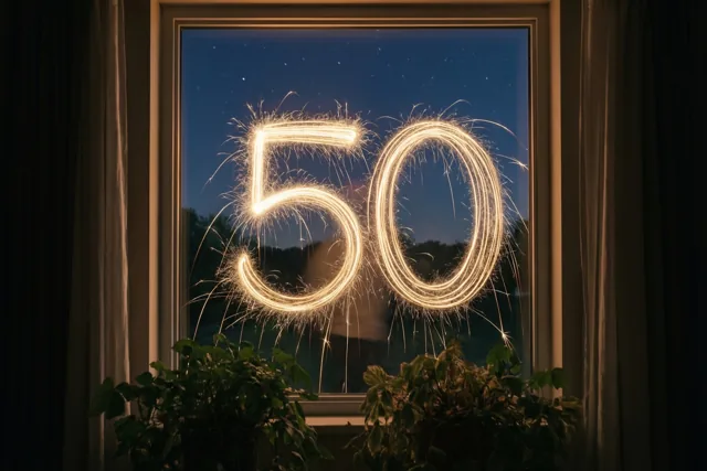 Door een raam met gordijnen en kamerplanten is 50 in gouden lichtsporen te zien tegen een sterrenhemel.