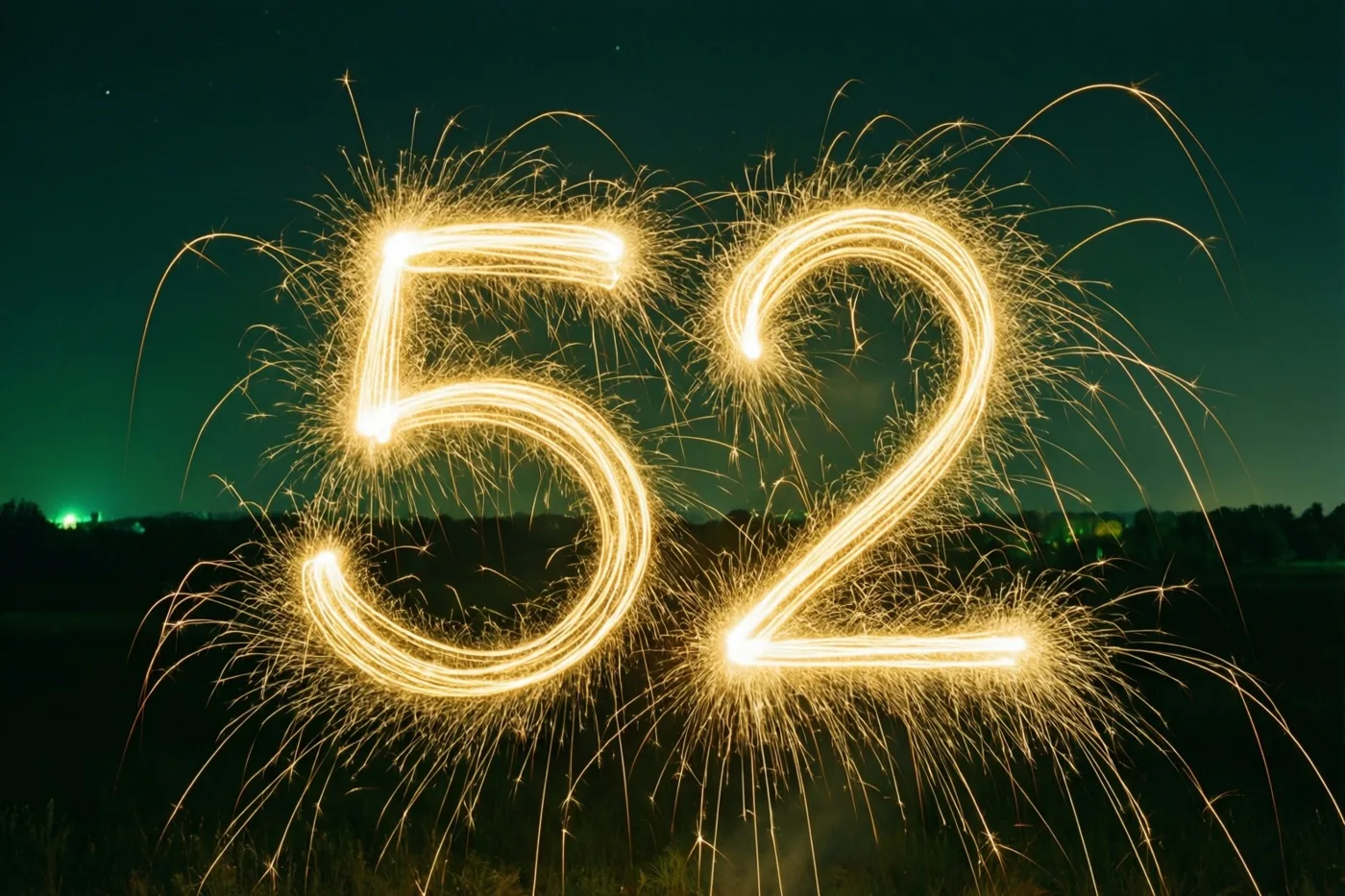 Gouden lichtsporen van sterretjes vormen 52 tegen een donkere nachthemel, met zwakke groene lichtjes in de verte.