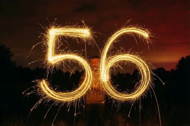 Gouden lichtsporen van sterretjes vormen 56 tegen een donkere nachtlucht met een roodoranje horizon.