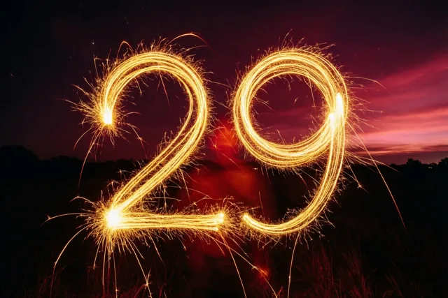 Gouden lichtsporen van sterretjes vormen 29 tegen een donkere nachtlucht met een roodpaarse horizon.