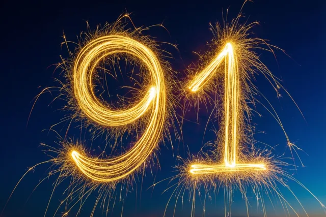 Gouden lichtsporen van sterretjes vormen 91 tegen een donkerblauwe nachtlucht.