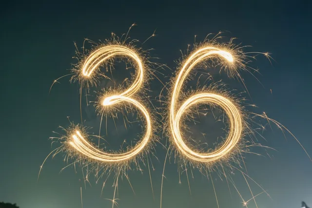 Gouden lichtsporen van sterretjes vormen het getal 36 tegen een donkerblauwe nachtelijke hemel.