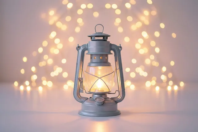 Een brandende grijze lantaarn staat op een witte ondergrond voor onscherpe warme feestlichtjes.