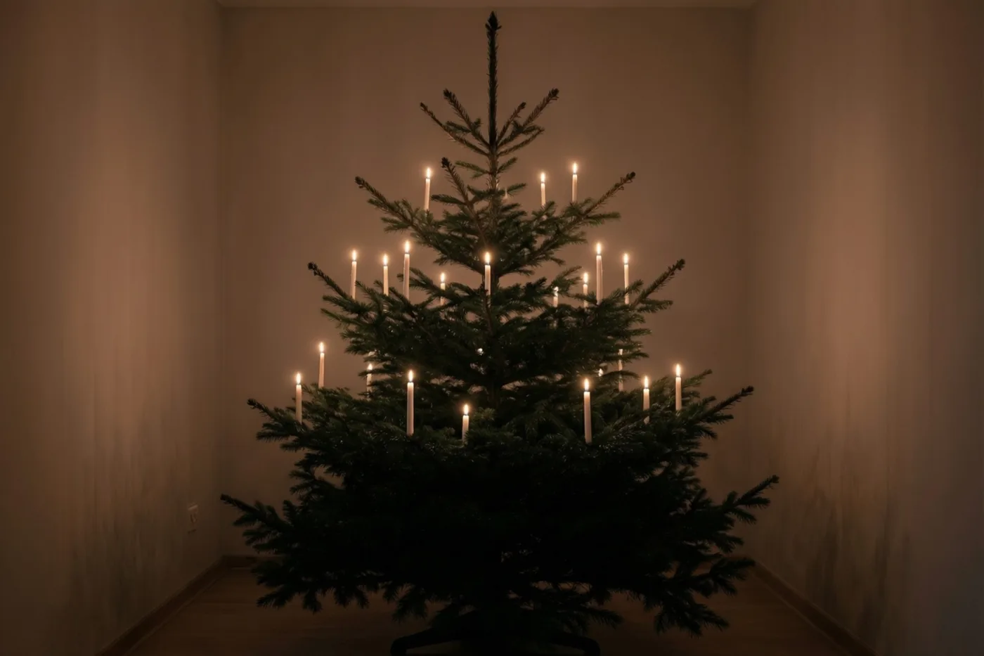 Echte kaarsen branden op de takken van een kerstboom in een schemerige kamer met donkergroene, warmbeige en zachtgele tinten.
