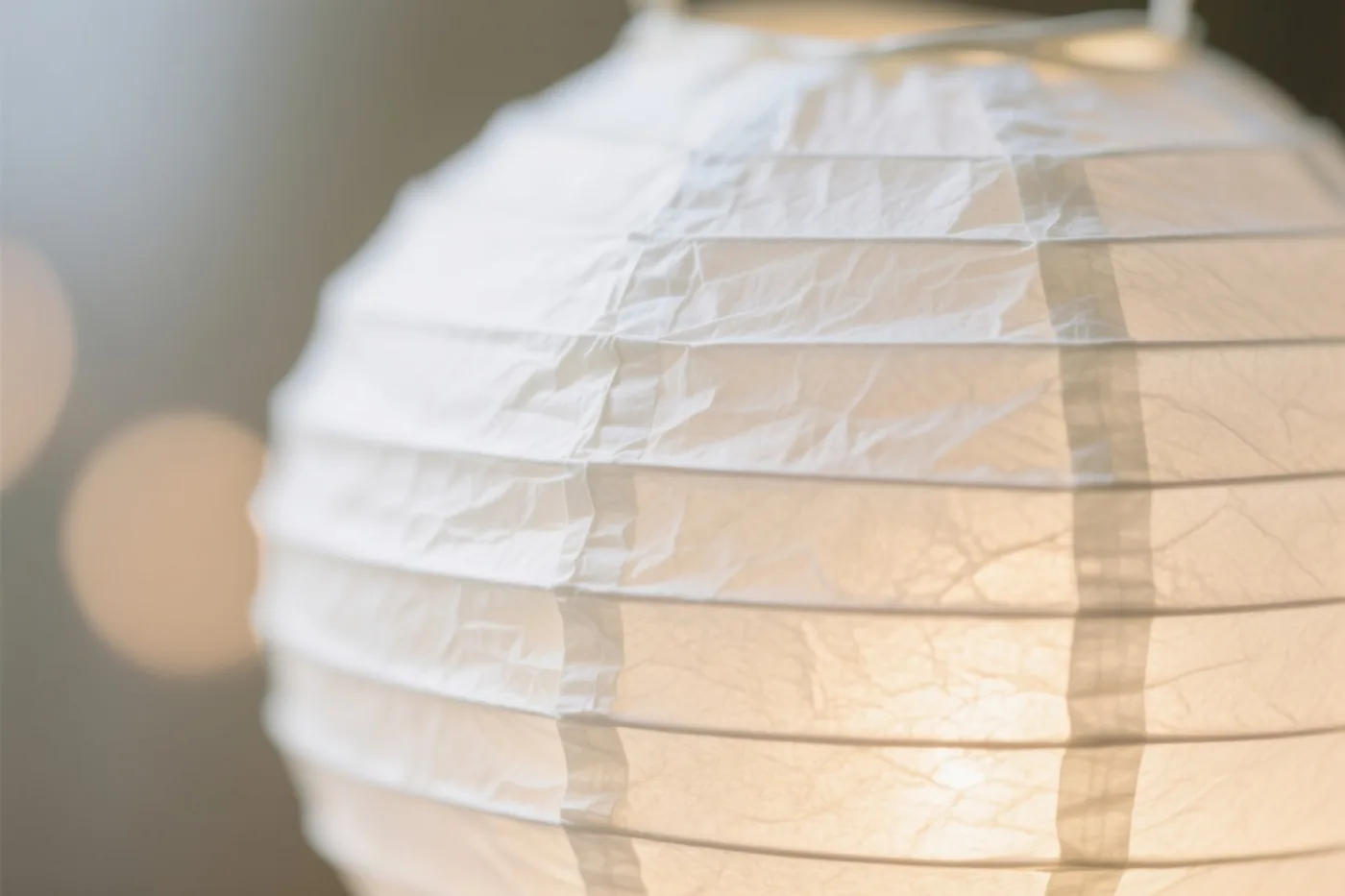 Een close-up toont een lichtgevende papieren lantaarn met duidelijk zichtbare vouwen en plooien in warme tinten.