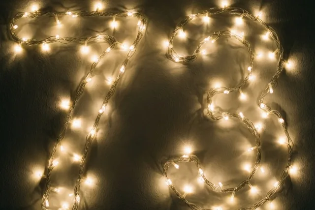 Warme lichtjes vormen het getal 73 tegen een donkere muur met een zachte gouden gloed.