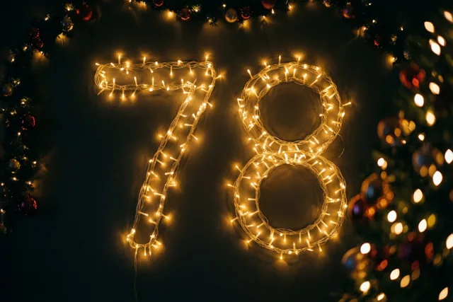 Warme lichtslingers vormen 78 tegen een donkere muur, met onscherpe kerstversiering in gouden en rode tinten eromheen.