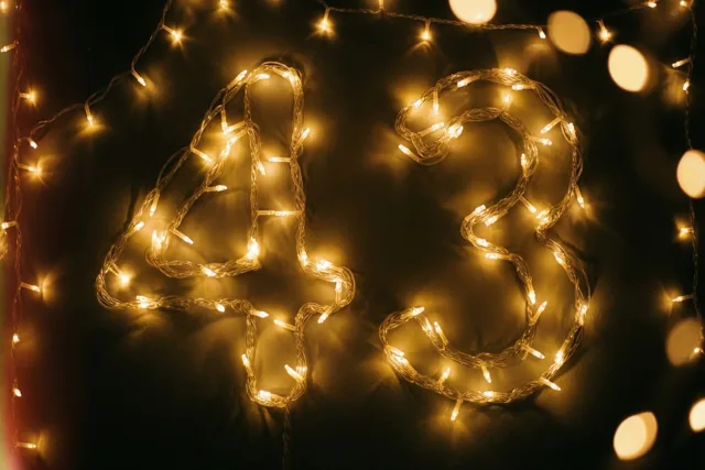 Warme lichtslingers vormen 43 tegen een donkere muur, met zachte onscherpe lichtjes op de achtergrond.