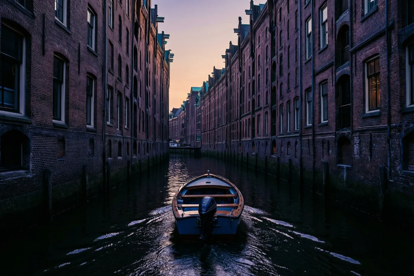 Een kleine motorboot vaart bij schemering over een smal kanaal tussen hoge, historische bakstenen gebouwen.