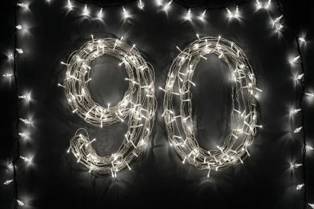 Het getal 90 is met warm gloeiende lichtjes gevormd tegen een donkere muur.