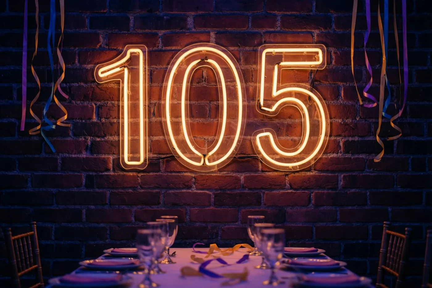 Een warm oplichtend neonbord met 105 hangt aan een donkere bakstenen muur boven een gedekte feesttafel met kleurrijke slingers.