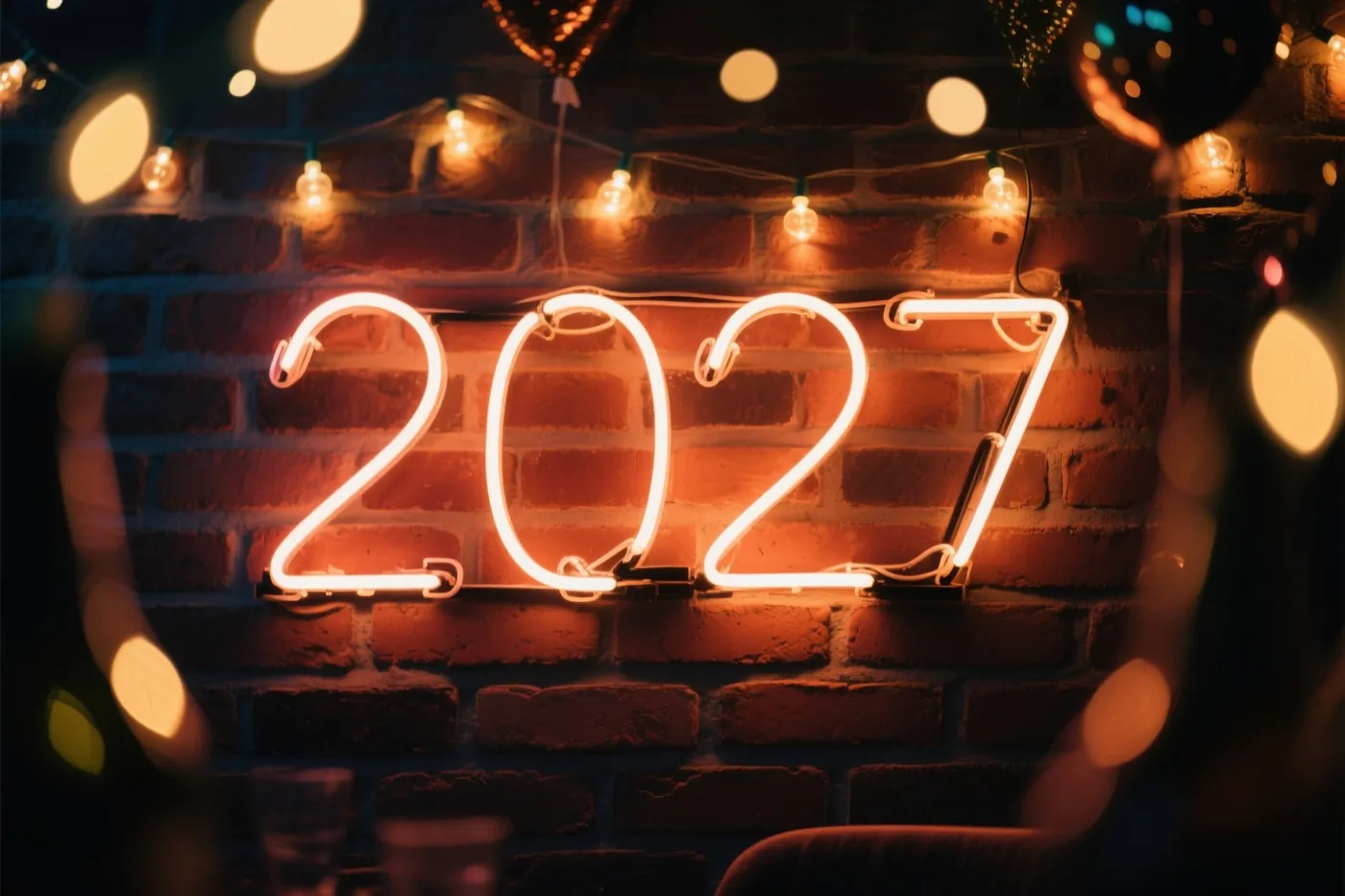 Een neonbord met het jaartal 2027 hangt aan een warm verlichte bakstenen muur, met lichtslingers en onscherpe lichtjes eromheen.