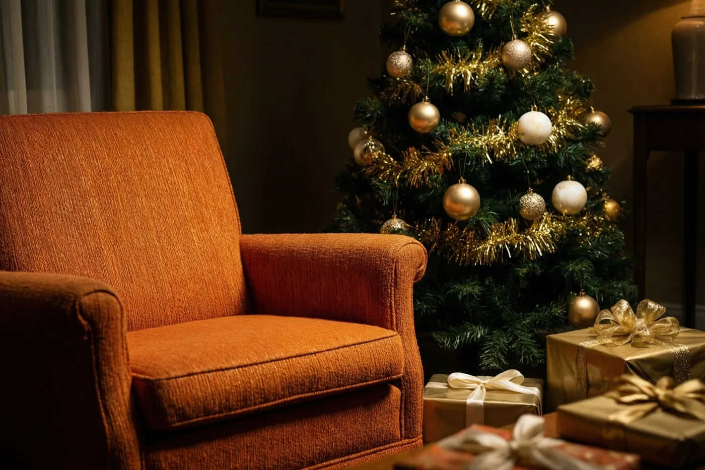 Een oranje zetel staat voor een kerstboom met gouden glitterslingers en versieringen, met ingepakte cadeaus onder de boom in warm licht.