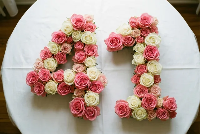 Van bovenaf zijn roze en witte rozen te zien die 41 vormen op een wit tafelkleed in zachte pasteltinten.