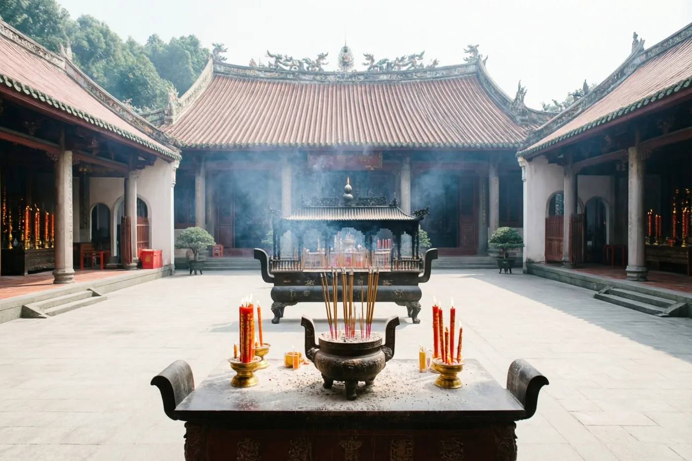 Op een Chinese tempelbinnenplaats met pannendaken en stenen bestrating staat een rokende wierookbrander, met brandende rode kaarsen op een houten tafel eromheen.