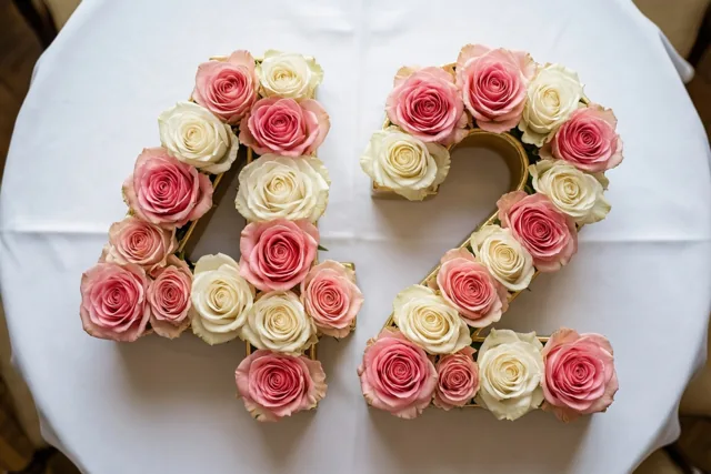 Roze en witte rozen vormen 42 op een wit tafelkleed, recht van boven gezien in zachte pasteltinten.