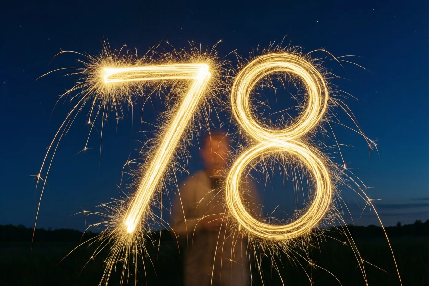 Gouden lichtsporen vormen 78 tegen een diepblauwe nachthemel met zwakke sterren, met een onscherpe persoon die de sterretjes vasthoudt op de achtergrond.