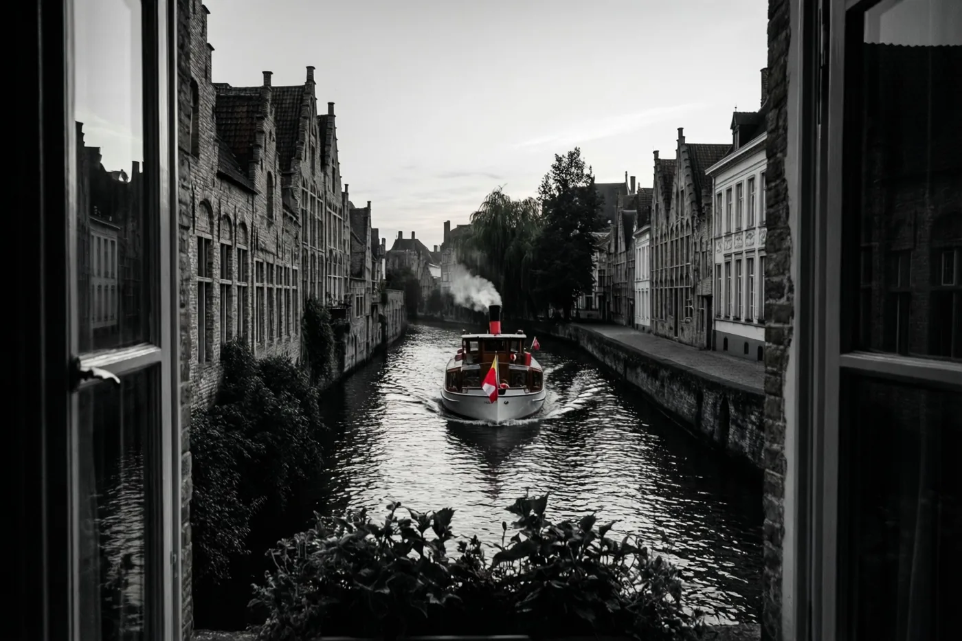 Door een raam is een stoomboot op een kanaal tussen oude Vlaamse gebouwen te zien, in zwart-wit met alleen kleur in de rode en witte vlaggen.