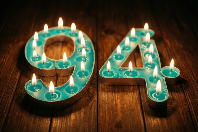 Brandende theelichtjes in turquoise houders vormen 94 op een donkere houten vloer.