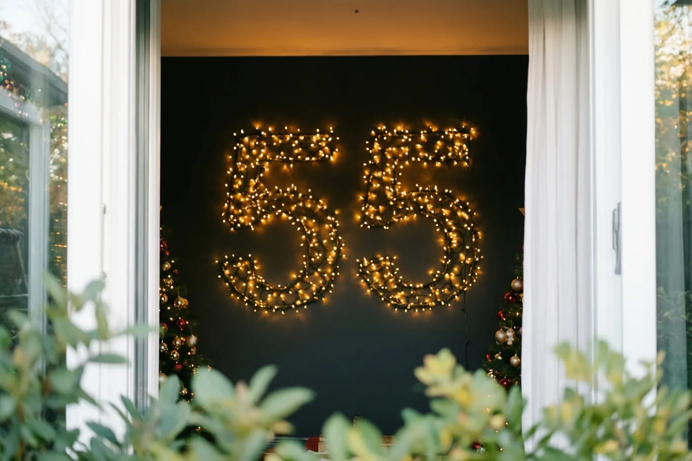 Door een open deuropening is 55 van warme lichtjes op een donkere muur te zien, met groen op de voorgrond.