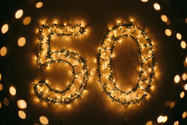 Het getal 50 is gevormd uit warm gloeiende lichtjes op een donkere muur, met wazige lichtjes op de achtergrond.