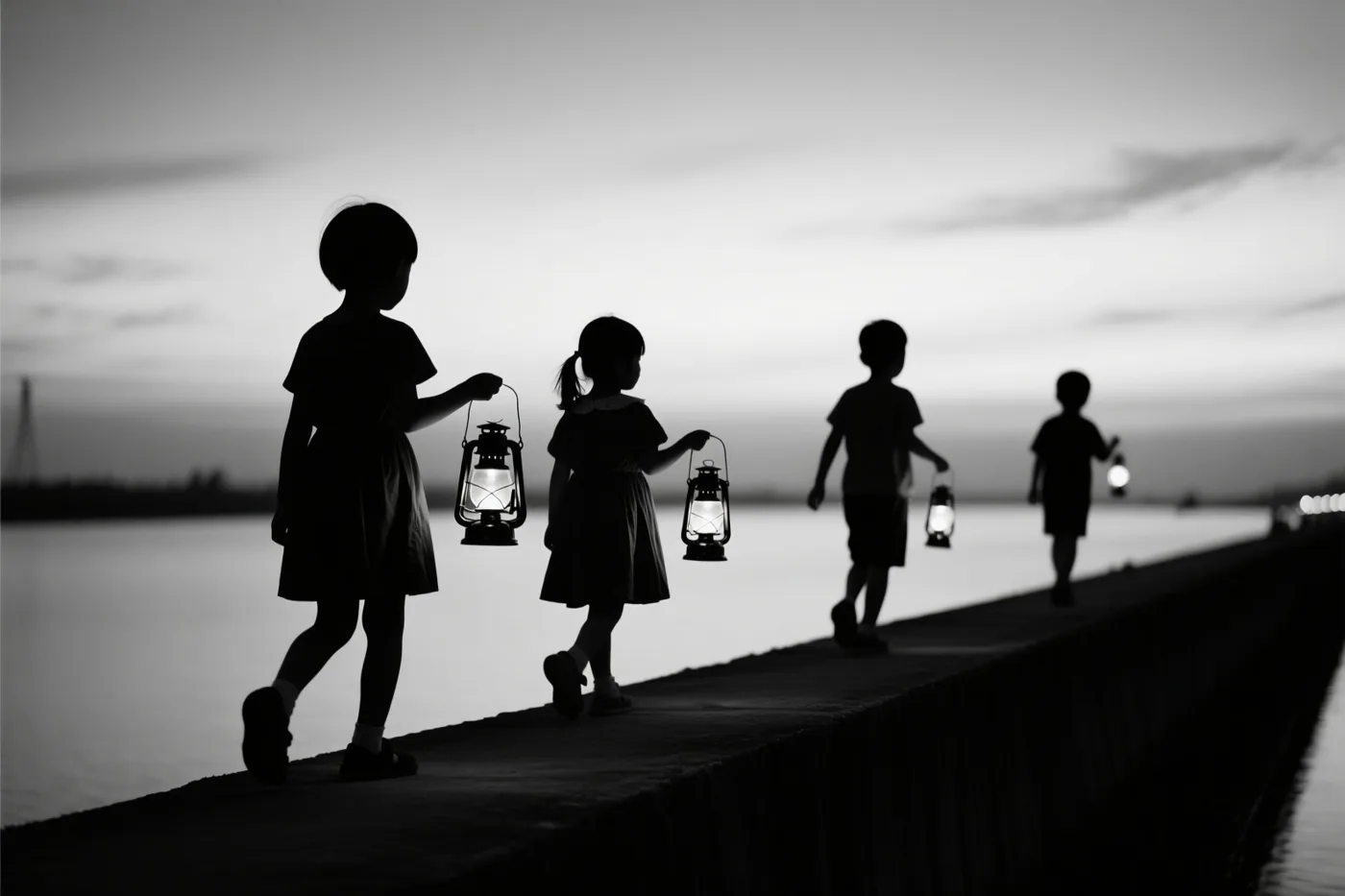 Een zwart-witbeeld toont de silhouetten van vier kinderen die met lantaarns over een lange dijk lopen bij schemering.