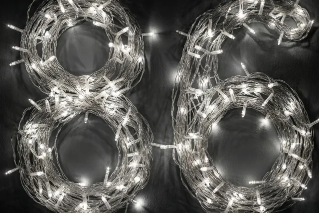 Lichtjes vormen 86 op een donkere muur, met warmwitte, onscherpe lichtvlekken op de achtergrond.