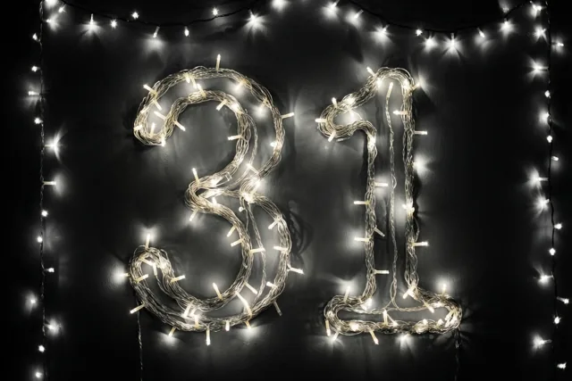 Het getal 31 is gemaakt van lichtjes op een donkere muur, omgeven door onscherpe warmwitte lichtvlekken.
