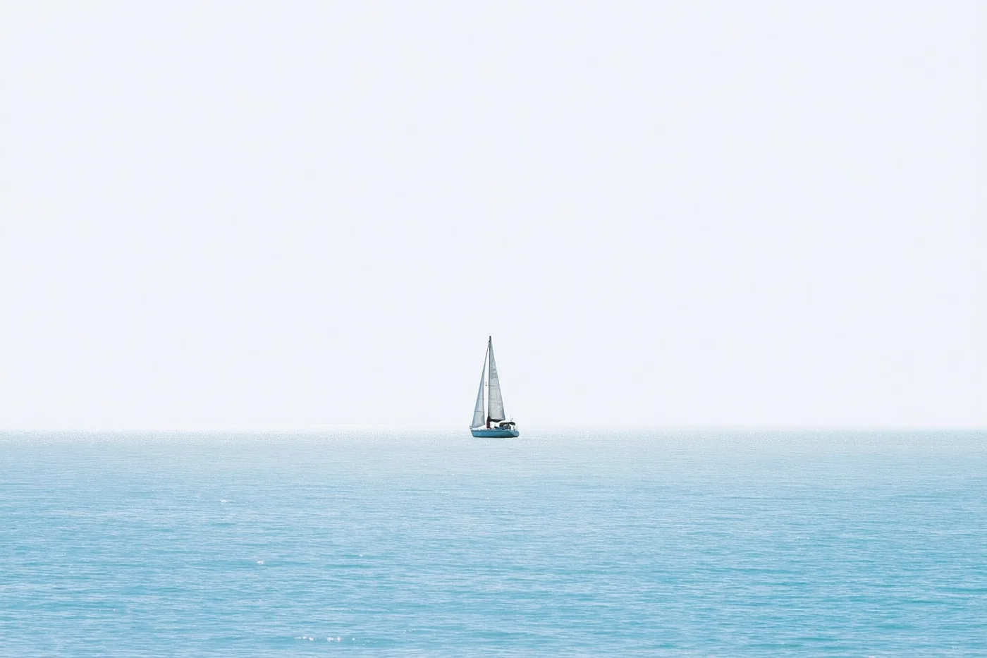 Een enkele zeilboot ligt aan de horizon van een rustige zee, met daarboven een heldere, heiige lucht in blauw en wit.