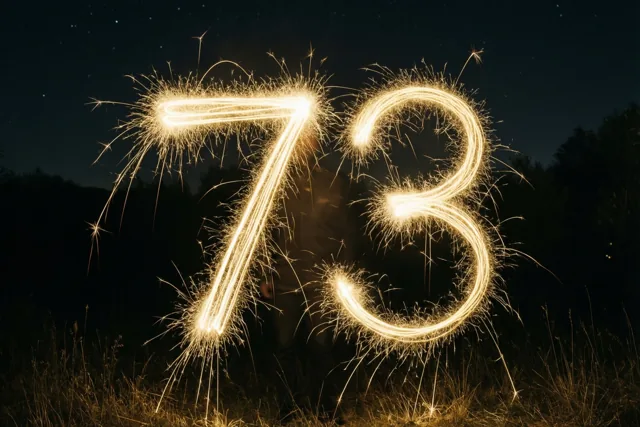 Gouden lichtsporen van sterretjes vormen 73 tegen een donkere sterrenhemel, boven gras met bomen op de achtergrond.